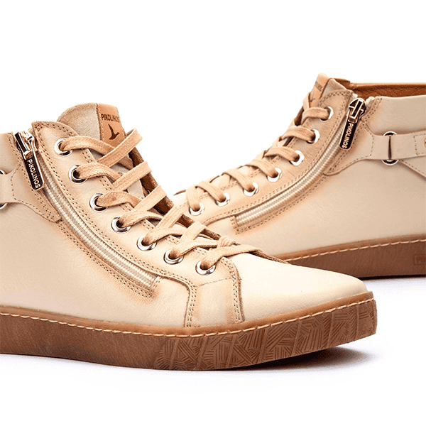 Zapatillas de running beige con suela de goma y cierre de cremallera lateral, ideales para estilo casual y deportivo.
