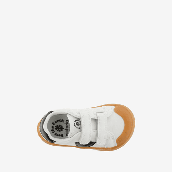 Zapatos deportivos infantiles de piel blanca y detalles en negro y marrón para niños, con doble velcro, comodidad y estilo en cada paso.
