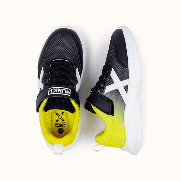 Zapatillas deportivas infantiles negro y amarillo con cierre de velcro y suela blanca, ideales para actividad física y uso diario. Diseñadas para niños en tiendas de calzado Luis Rico.