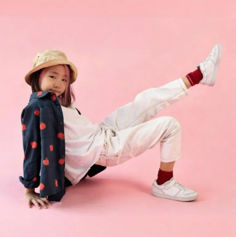 Niña con deportivas blancas sobre fondo rosa